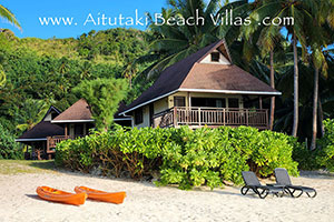 White sandy beachfront with coconut trees and turquise lagoon on Aitutaki Island in the Cook Islands